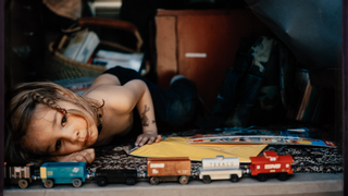Little boy laying on his side playing with trains