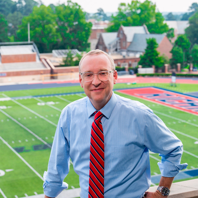 President Hallock poses at a ledge overlooking the football field.
