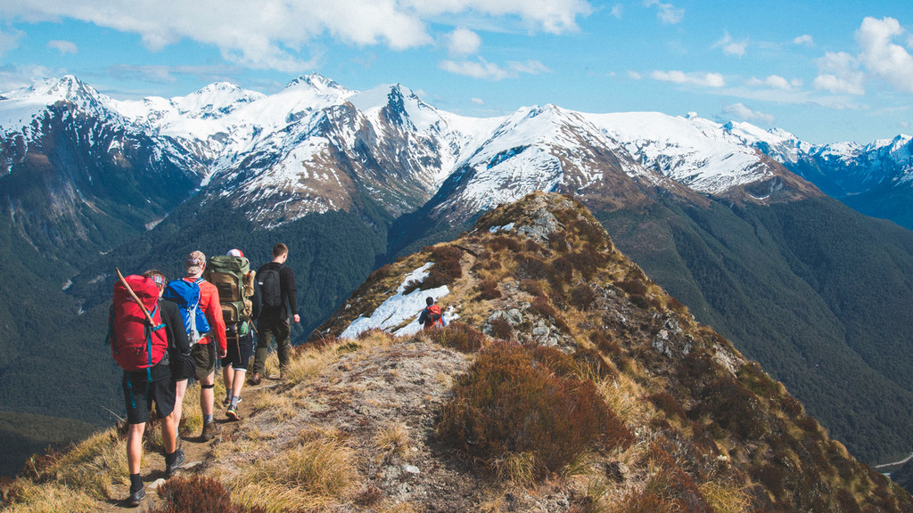 Students hike along a path on a vast mountain range in New Zealand.