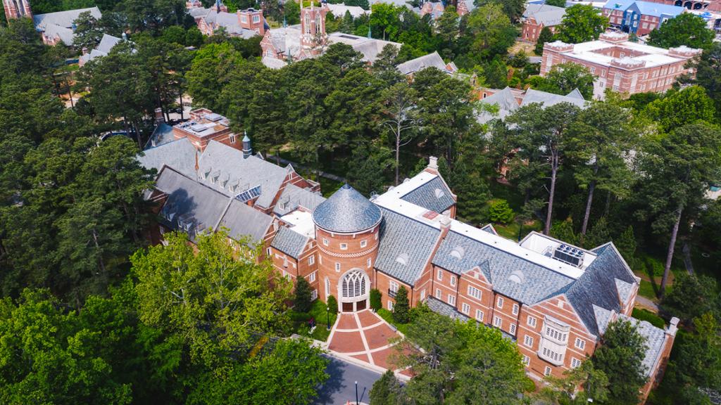 An aerial view of the Robins School of Business, a brick building surrounded by green trees.