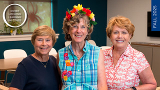 Three women standing in an open room, leaning on a railing