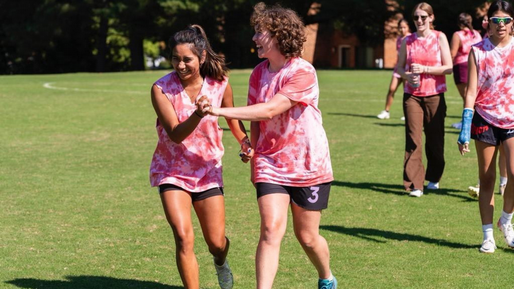 two students laughing while playing frisbee