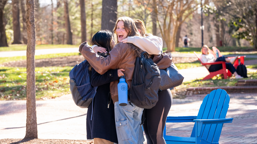 Three students hugging on the Forum