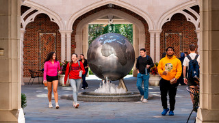 Students walking past globe