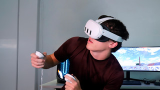 A student wears a virtual reality headset while holding controls.