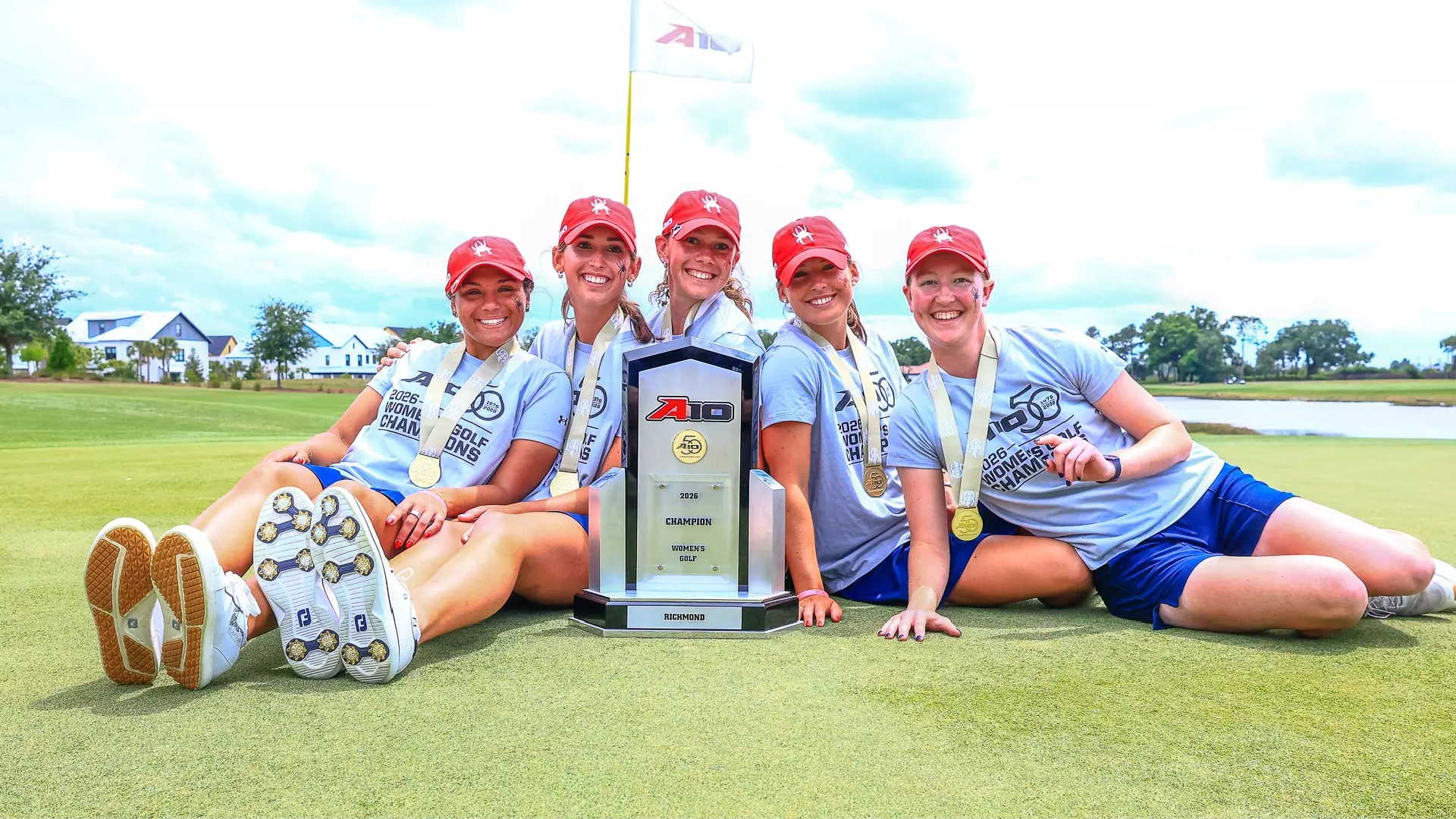 The University of Richmond women's golf team posing with the A-10 championship trophy.