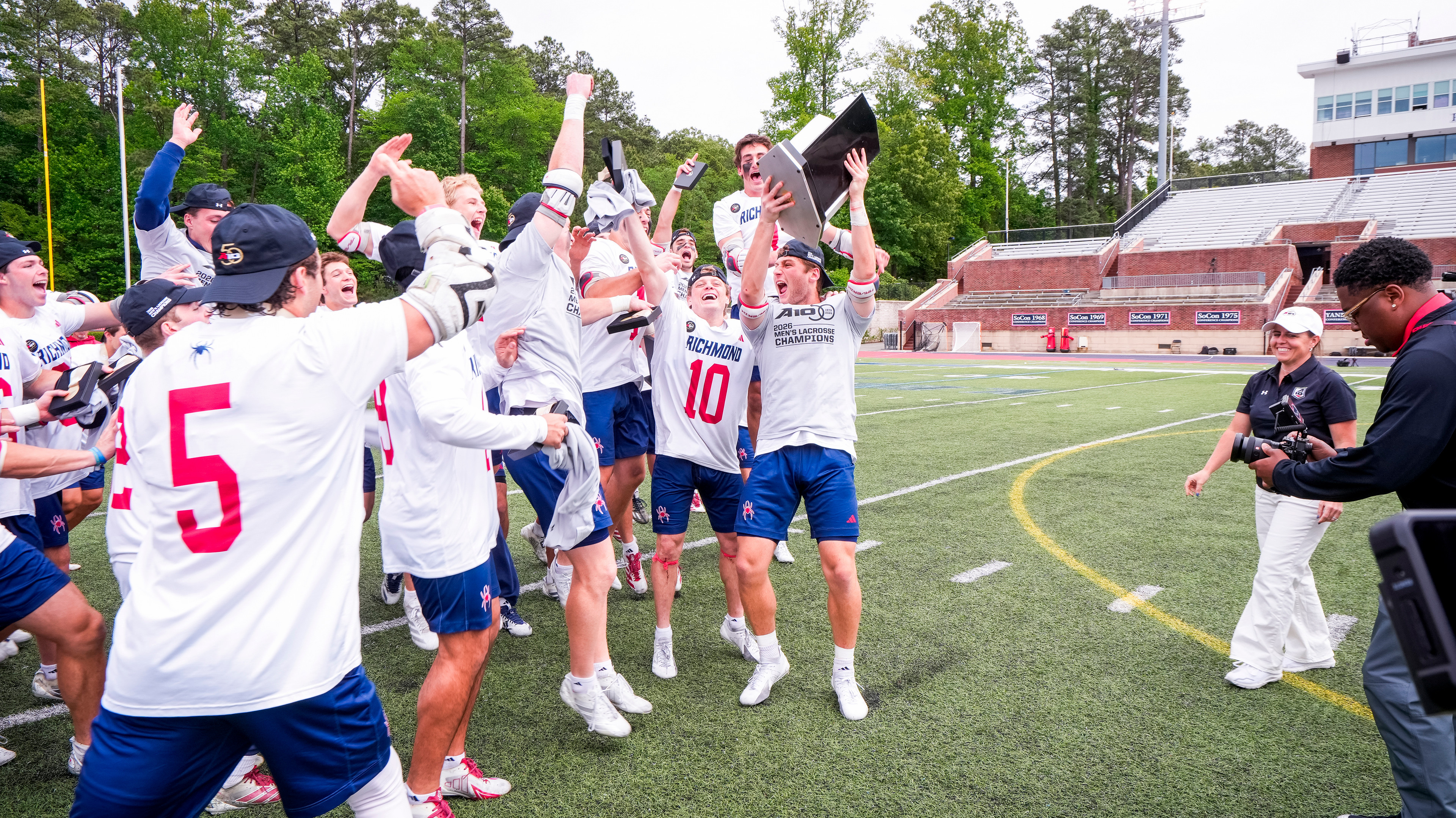 The University of Richmond men's lacrosse team celebrates thier A-10 win by hoisting the trophy over their heads.