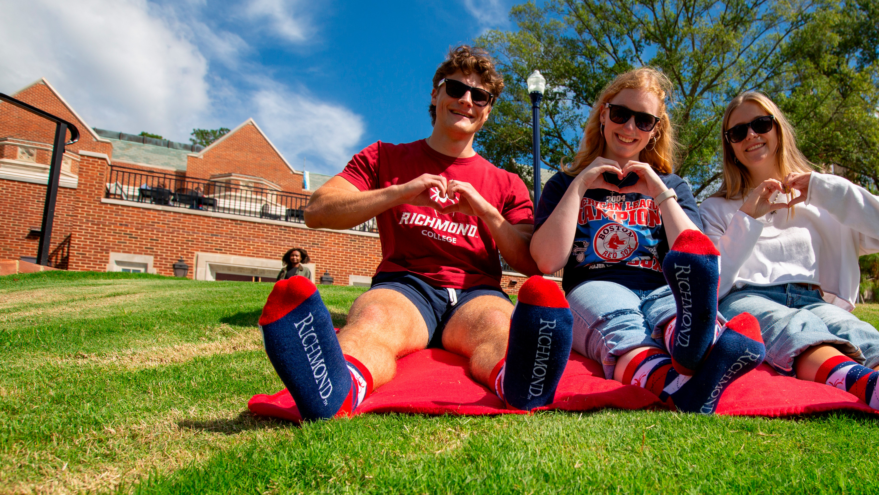 A photo of three students wearing sunglasses, making heart hands, and modeling the University of Richmond branded socks that were given out as thank you gifts to donors.