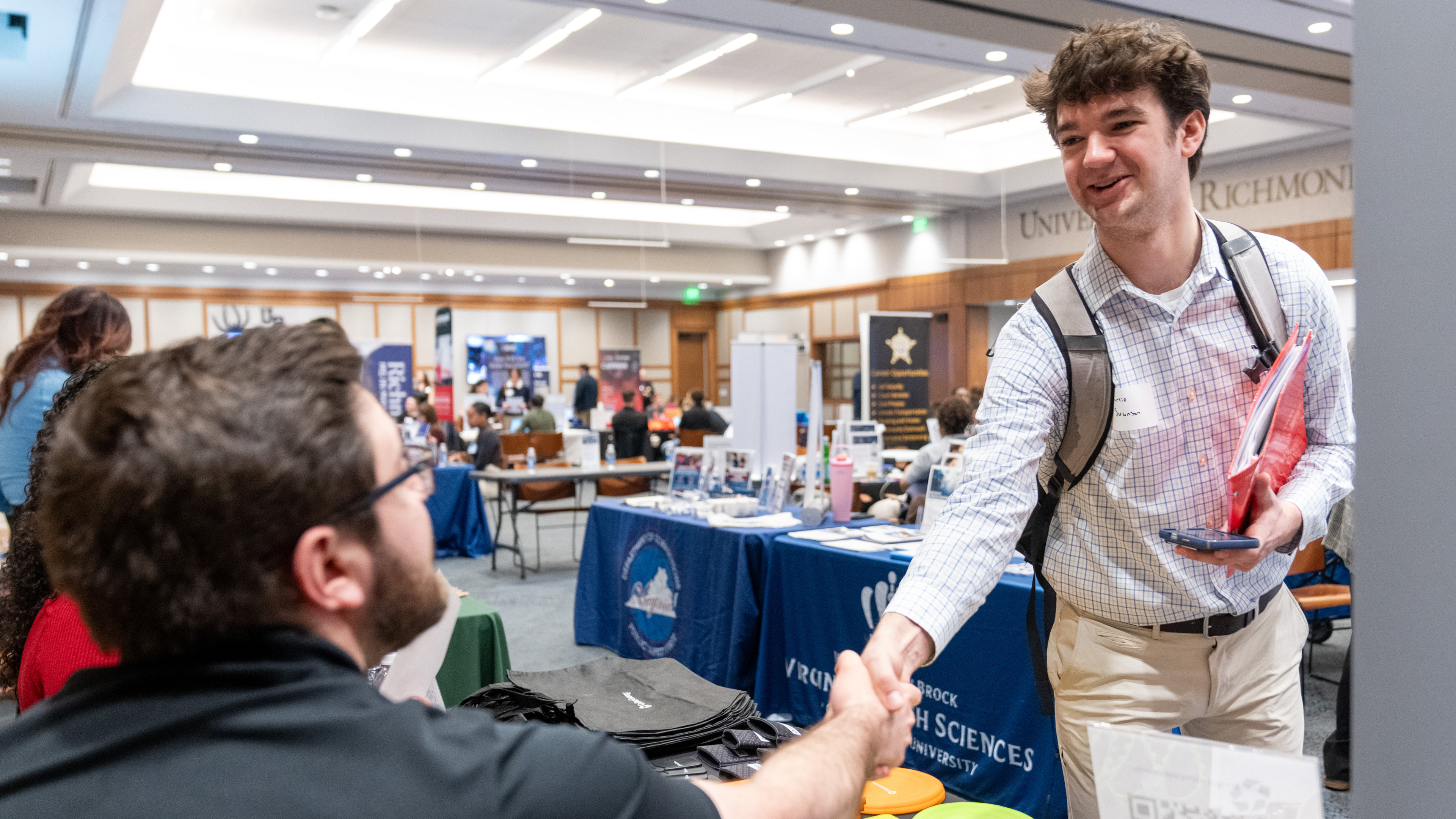 A student shakes hands with a potential employer at a carer fair at the University of Richmond.