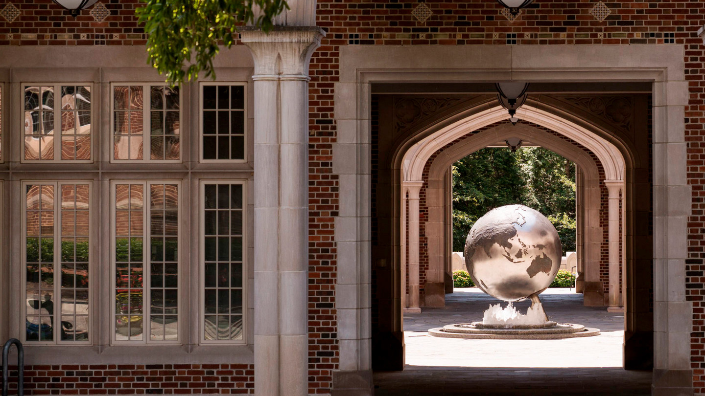 The globe fountain framed by an arch of the Carole Weinstein International Center at the University of Richmond.