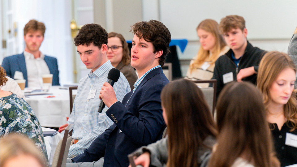 A student holding a microphone asks a question at the Jepson EDGE career program.
