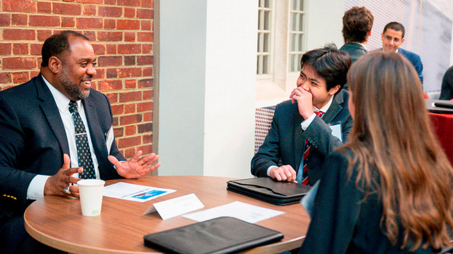 2002 alum Ed Gates Jr. of Capital One talks with two students at the Robins Pro career conference.